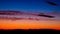 Panorama of tops of forest against background of sky illuminated by setting sun. Blue, orange, black