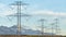 Panorama Towering power lines in the valley against snow capped mountain and blue sky