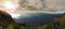 Panorama of traveler on top of mountain, he standing on the rock watching a nice sunrise