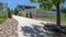 Panorama Tree in the middle of a concrete and stone pathway against homes and blue sky