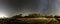 Panorama of very clear deep starry skies with Milky Way above harvested field and wild Scandinavian pine forest, autumn time