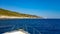 Panorama view from a boat, on the blue greek sea with a green and rock coastline