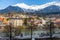 Panorama view of colorful buildings and mountains across from the flowing river of Innsbruck, Austria