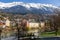 Panorama view of colorful buildings and mountains across from the flowing river of Innsbruck, Austria