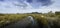 Panorama view of crack earth and dry water among mangrove forest with blue sky, clouds and long mountain in background