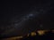 Panorama view of milkyway stars in dark night sky above cliff rock formation in Uyuni Sur Lipez Bolivia South America