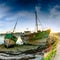 Panorama view of old fishing boat wrecks stranded on a rocky beach at sunset