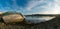 Panorama view of old fishing boat wrecks stranded on a rocky beach at sunset in the harbor