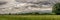 A panorama view of Pendle Hill and farm land with rain clouds.