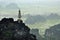 Panorama view of rice fields, rocks and mountaintop pagoda from