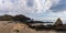 Panorama view of a secluded sandy beach on a wild mountainous coastline with rocks