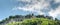 Panorama view of a steep cliff and woodland mountain top with powerlines running over it