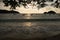 Panorama view of sunset and silhouette of trees and boats on the beach