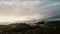 Panorama view to sunset on beach. Surfer holding a surfboard and coming into the water. Beautiful seascape.