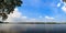 Panorama view of a tranquil lake with a blue sky background.