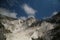 Panorama of a white Carrara marble quarry in Tuscany. Mountains of the Apuan Alps, blue sky