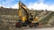 Panorama Yellow excavator and orange traffic delineator post beside a mountain road