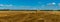 Panorama of yellow golden bales of wheat hay straw stacked in a heap in stubble field