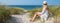 Panorama young woman sitting in the dunes