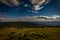 Panoramatic view from peak of Velky Keprnik with pine trees, green grass and dark blue cloudy sky in Jeseniky