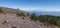 Panoramatic view of volcanic landscape with lush green pine trees, colorful volcanoes and white clouds at path Ruta de