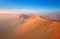 Panoramic, aerial, artistic photo of Namib dunes.  Early morning Namib desert covered in mist. Orange dunes of Namib from above.