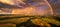 Panoramic, aerial photo of dramatic rainbow over european landscape. Large late evening rainbow over city and hills in