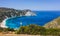 Panoramic aerial photo of man standing on top of a rock with an exciting feeling of freedom, looking at Petani Beach