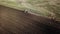 Panoramic aerial view of agricultural cultivated field with tractor performing fall tillage