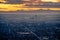 Panoramic aerial view of city with silhouetted mountain and golden sky at sunset