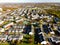 Panoramic aerial view of a cluster of houses with a swimming pool, tennis court and parking lots, captured by a drone
