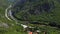 Panoramic aerial view of mountains and river next to traffic road and trail