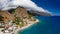 Panoramic aerial view of a small coastal village with towering, cloud covered mountains Agia Roumeli, Crete, Greece