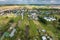 panoramic aerial view of small provincial town or big eco village with wooden houses, gravel road, gardens and orchards