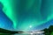 Panoramic Aurora borealis, Northern green lights with full moon and stars in the night sky over mountain lake, mirrored reflection
