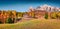 Panoramic autumn view of Dolomite Alps with yellow larch trees and traditional italian building.