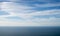 Panoramic beautiful view of a serene horizon where the blue sky with clouds meets the calm sea or ocean