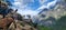 Panoramic closeup of a herd of goats on a hill, with a mountain in the background on a sunny day