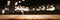 Panoramic empty clean wood counter table top on blur street night cafe background use for pub coffee shop montage dark scene,