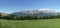 Panoramic of the French Alps : green field in foreground of the mountains