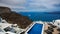 A panoramic image from Santorini with resort swimming pool and sea view to caldera