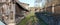 Panoramic landscape of autumn November  village road with barns sheds  and wooden fences