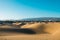 Panoramic landscape view of maspalomas sand desert dunes with the city and mountains in background on a sunny summer day