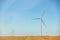 Panoramic landscape view of new white modern wind turbine farm power generation station against clear blue sky and field