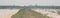 Panoramic muddy farm road leads to horizontal line with sunset at flooded rice field in North Vietnam