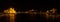 Panoramic night view on Hungarian Parliament Building located at the bank of the Dunabe river with famous Chain Bridge connecting