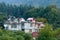 Panoramic Old Hotel cottage retro style building surrounded with pine woodland trees in springtime himalayan mountain valley.