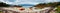 Panoramic photo of colorful kayaks on the sandy seashore, hills, blue sky in Norway.