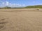 Panoramic photo of dry salt pans of ocher color. Blue sky with tropical clouds and mountains with vegetation. Martinique, French