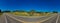 Panoramic photo of road between hills in Minas Gerais, Brazil, with blue sky and pasture with livestock beside